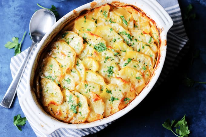 Boulangere Potatoes in white baking dish with spoon on a side