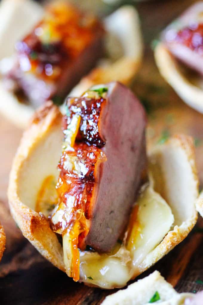 Tea Infused Orange Duck Bites with Brie are a perfect appetizer for Easter or any other Holidays. They are full of flavor with Stash Lemon Ginger Tea infused duck breast, seared to perfection, smothered with Lemon Ginger Tea Orange Glaze and topped on the melted brie toasts for the ultimate bite. Close up shot of Orange Duck Bite with Brie Cheese