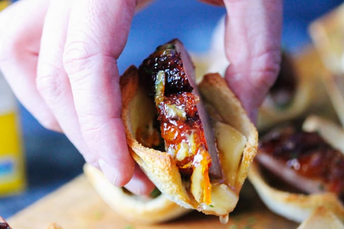 Tea Infused Orange Duck Bites with Brie are a perfect appetizer for Easter or any other Holidays. They are full of flavor with Stash Lemon Ginger Tea infused duck breast, seared to perfection, smothered with Lemon Ginger Tea Orange Glaze and topped on the melted brie toasts for the ultimate bite. Horizontal shot of picking up an orange duck bite with brie