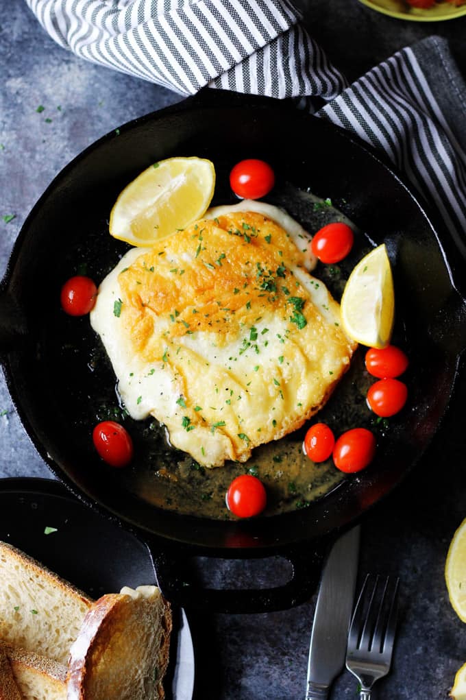 Saganaki - Greek Fried Cheese in a skillet with lemons and cherry tomatoes