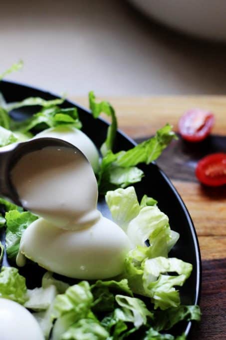 Spooning over mayonnaise sauce on the eggs