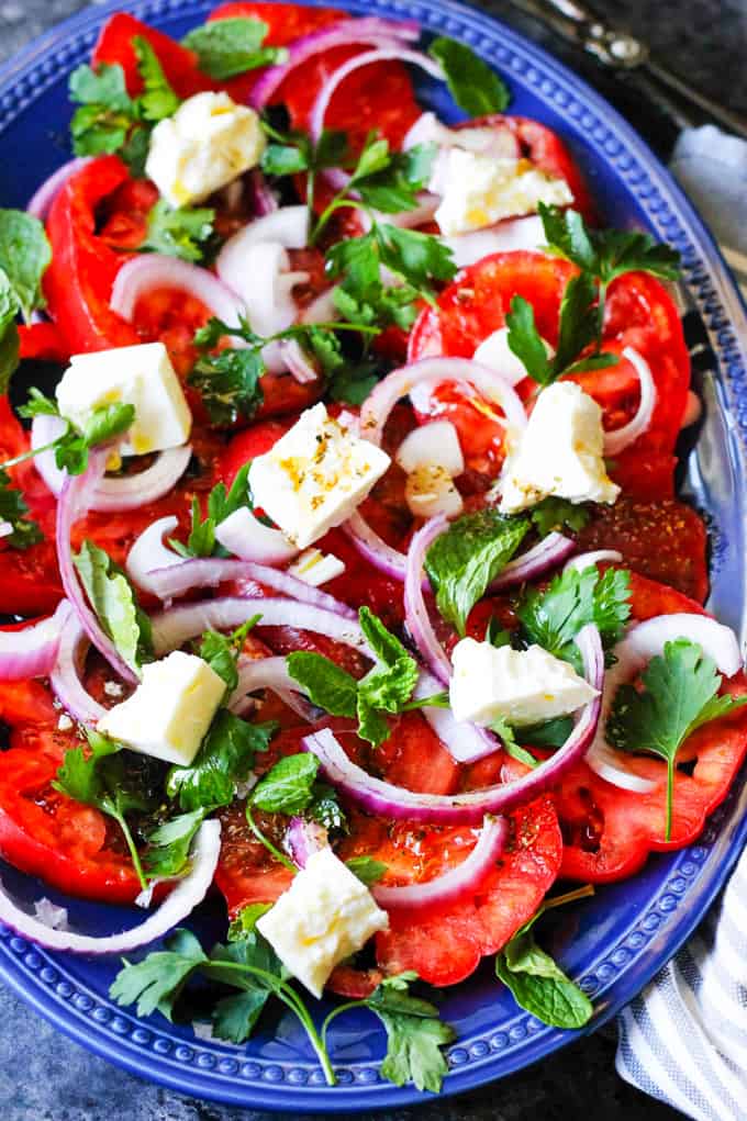 Tomato Feta Salad with herbs on a blue serving plate