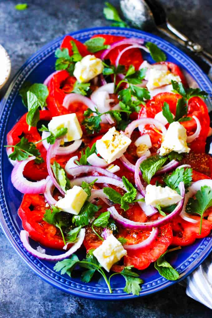 This Tomato Feta Salad is as simple as it gets, and it is super delicious! When ripe, juicy tomatoes are in season you'll want to eat it every day. It contains a few simple ingredients and it comes together in no time at all. Tomato and Feta Salad on a blue serving plate