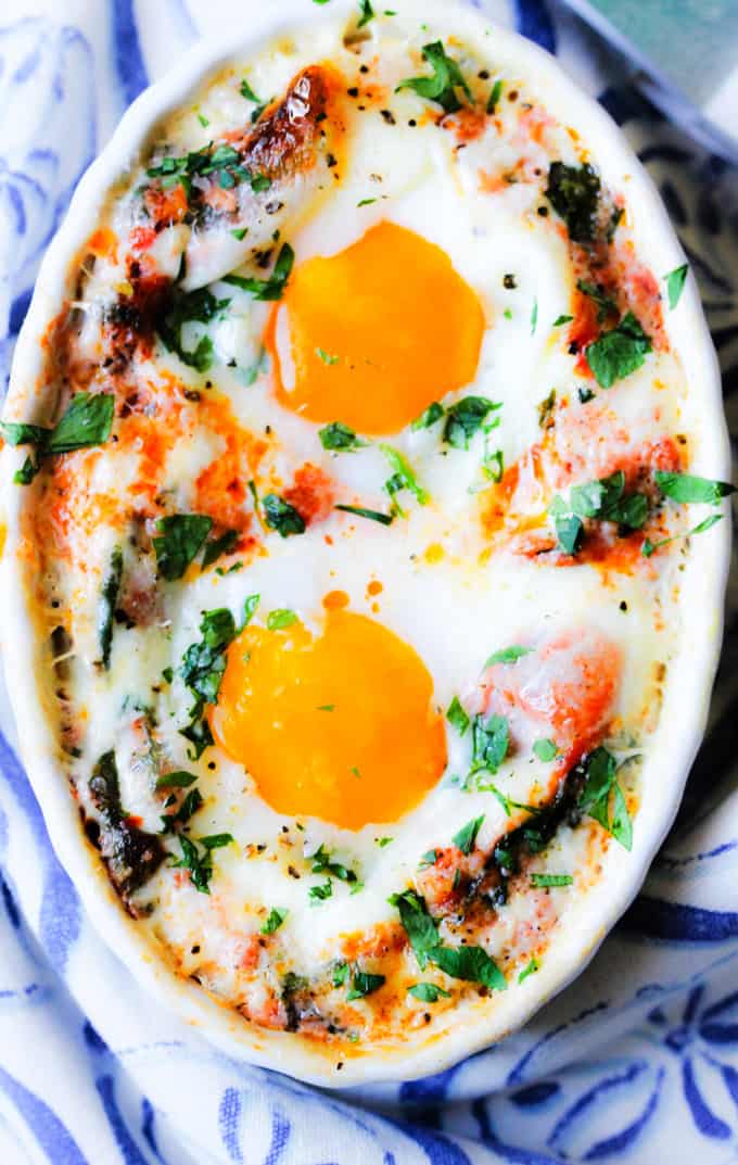 Baked eggs in cream tomato spinach sauce in white ramekin