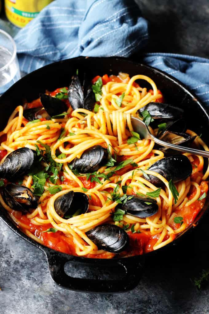 Pasta with Mussels and tomato sauce in a black skillet
