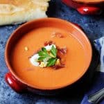 Salmorejo in bowls with ham and egg on top and bread on a side