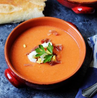 Salmorejo in bowls with ham and egg on top and bread on a side