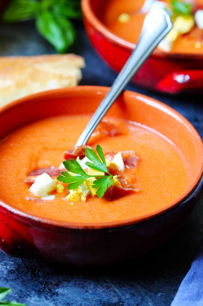 Close up shot of Salmorejo soup in orange bowl with spoon.
