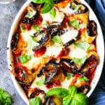 Eggplant Rollatini Parmigiana in a casserole dish with towel on a side