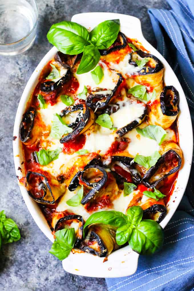 Eggplant Rollatini Parmigiana in a casserole dish with towel on a side