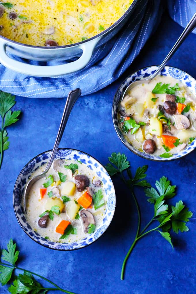 Overhead shot of mushroom soup in two bowls with a pot in the background