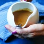 Hands holding easy homemade gravy in serving dish with spoon