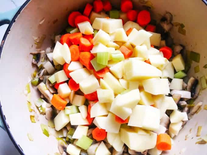 carrots, onions and potatoes added to a pot of mushrooms and onions