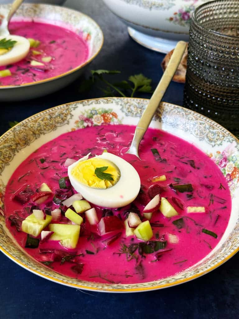 Cold borscht soup garnished with a hard boiled egg and cucumber
