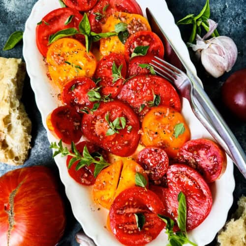 Overhead of heirloom tomato salad on a white platter