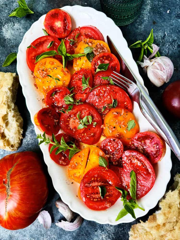 Overhead of heirloom tomato salad on a white platter