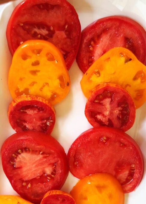 The tomatoes are arranged on a white serving plate for this tomato garlic salad
