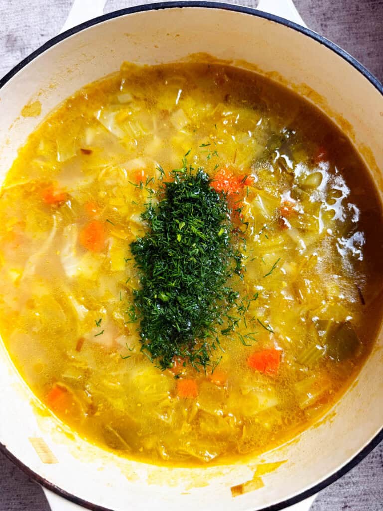 Dill added to a bowl of kapusniak