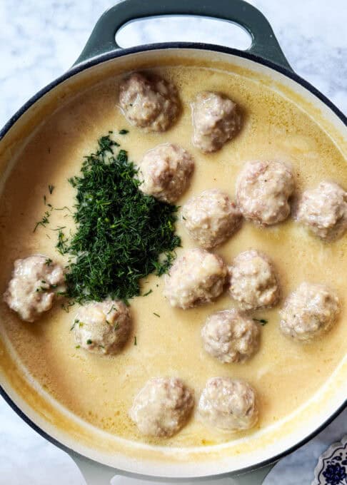Pot with boiled meatballs and dill in sauce