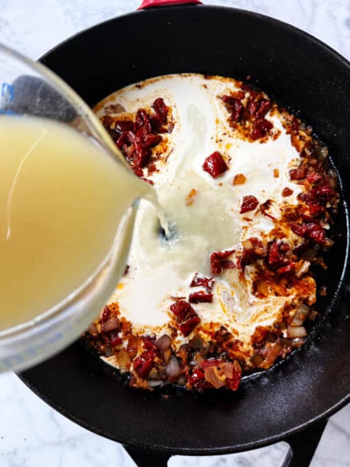 Adding chicken broth to the pan
