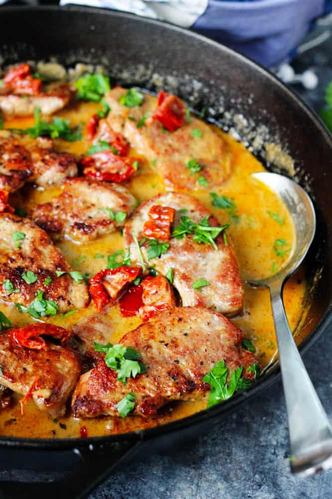 Finished pork tenderloin medallions recipe in a skillet with serving spoon.