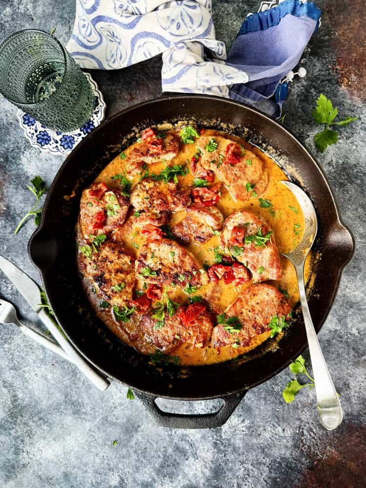 Pork tenderloin medallions in a skillet with a serving spoon