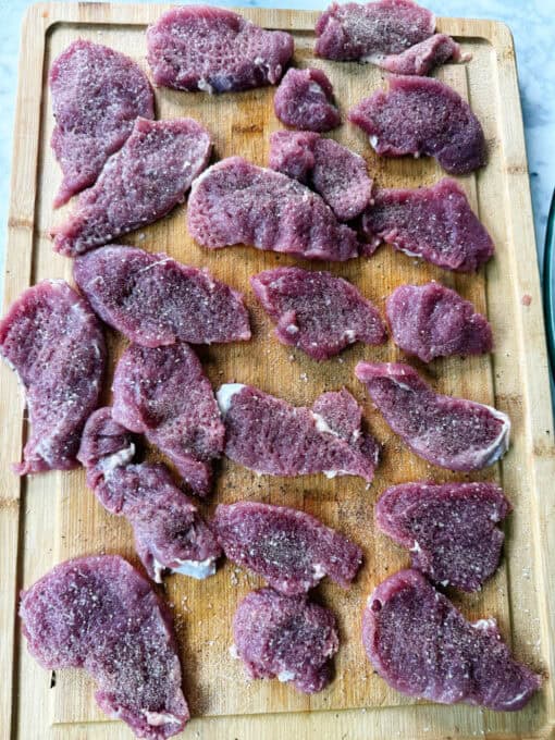 Seasoning pork medallions on a chopping board