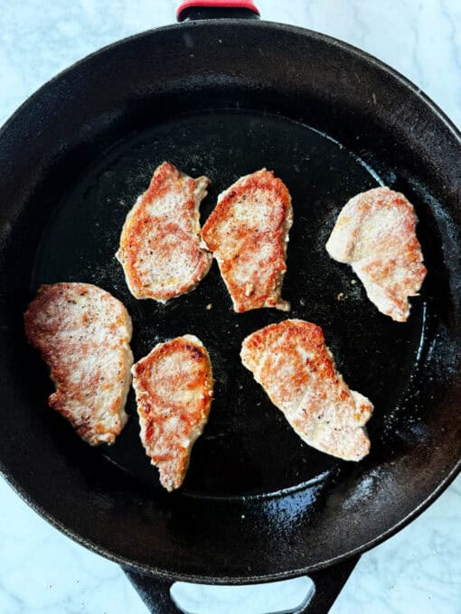 Pork being seared in a skillet