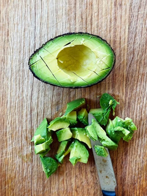 Overhead view of half an avocado next to sliced avocado cubes