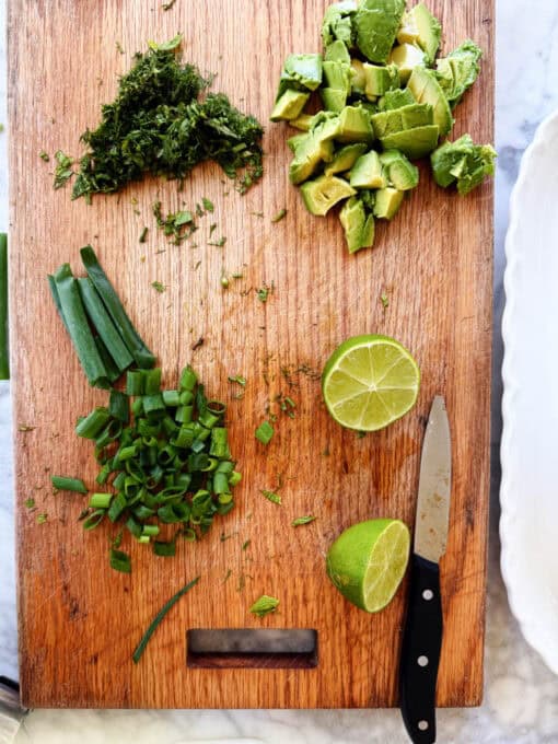 Overhead of scallions, mint and dill chopped up on a cutting board
