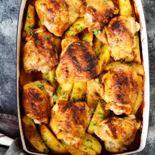 Roasted chicken thighs and potatoes in a baking dish