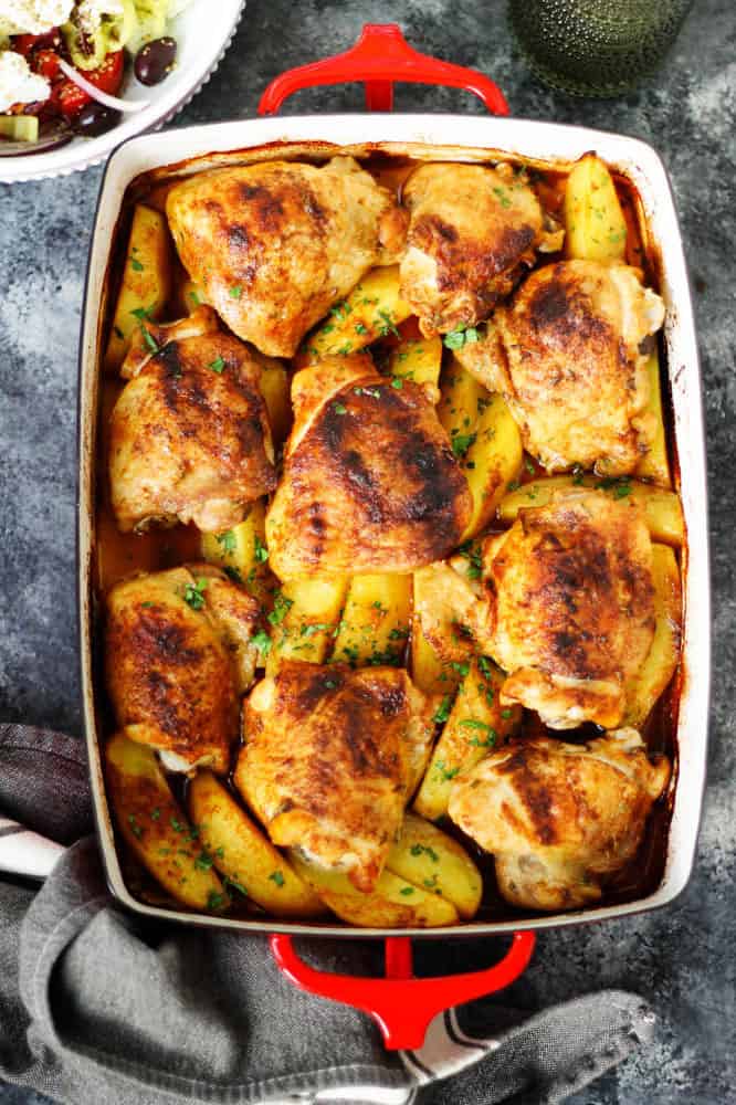 Roasted chicken thighs and potatoes in a baking dish