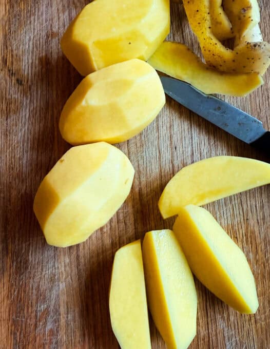 Peeled potatoes on a chopping board