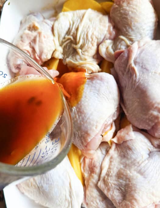 Pouring marinade over the chicken thighs