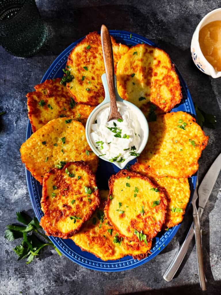 A plate of german potato pancakes with dipping sauce in the center