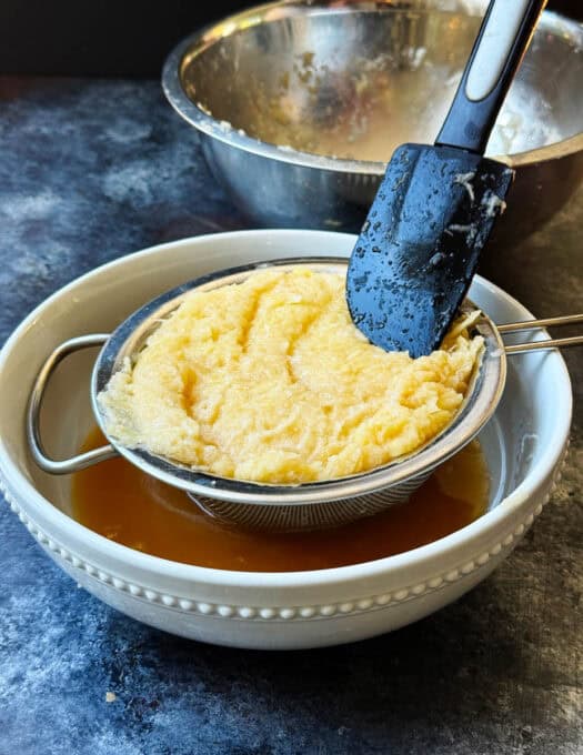 Liquid is draining out of the potatoes into a bowl
