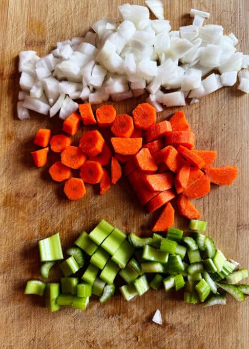 Chopped up onions, carrots, and celery on a chopping board
