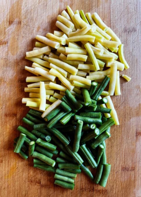 Chopped up yellow and green beans on a cutting board