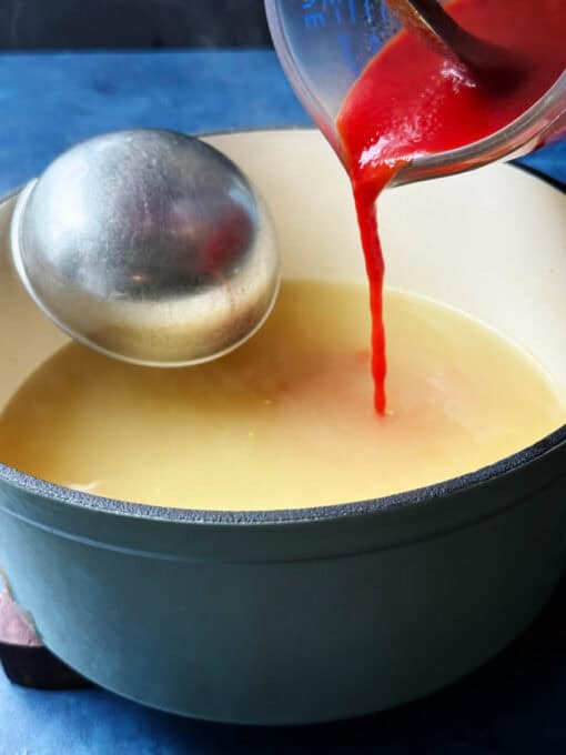 Tomato paste and broth mixture poured into pot of sauce