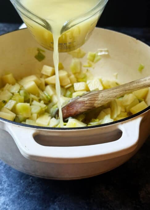Broth is being poured into the Dutch oven