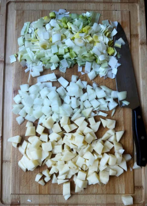 Chopped up onions, leeks and potatoes on a chopping board