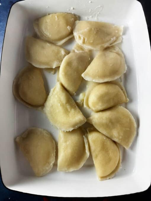 Cooked pierogi in a white baking dish