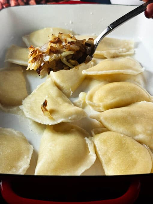 Kielbasa being spooned over the pierogi