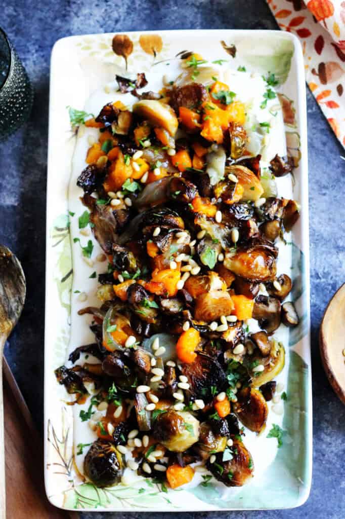 Roasted Brussels sprouts with carrots and pine nuts on a decorative serving platter.